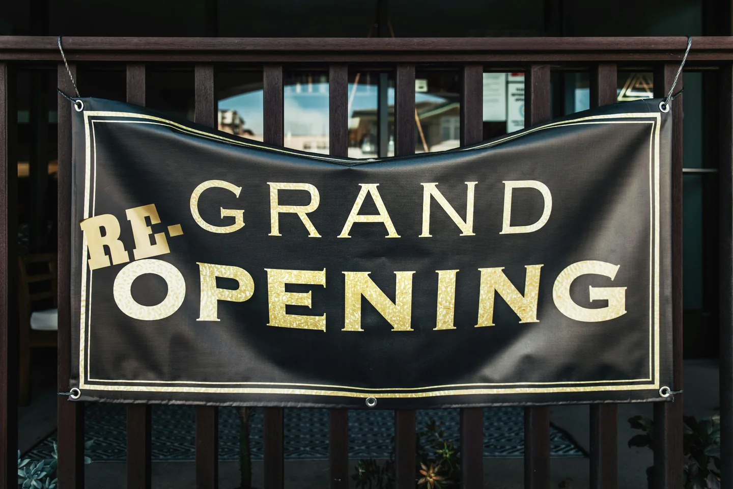 Printed soft-signage banner mounted across a commercial exterior railing.