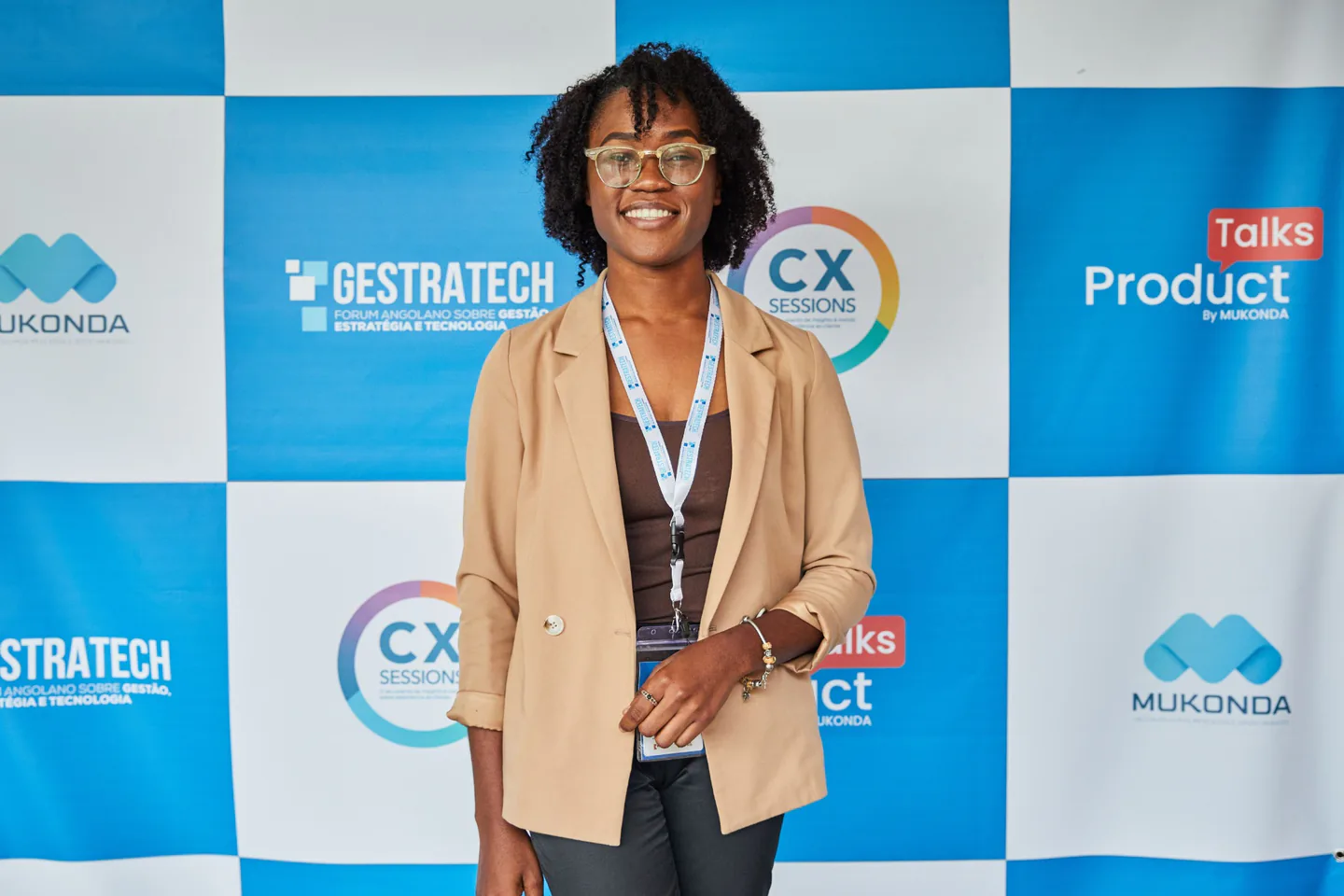 Event attendee standing in front of a blue and white branded media wall.