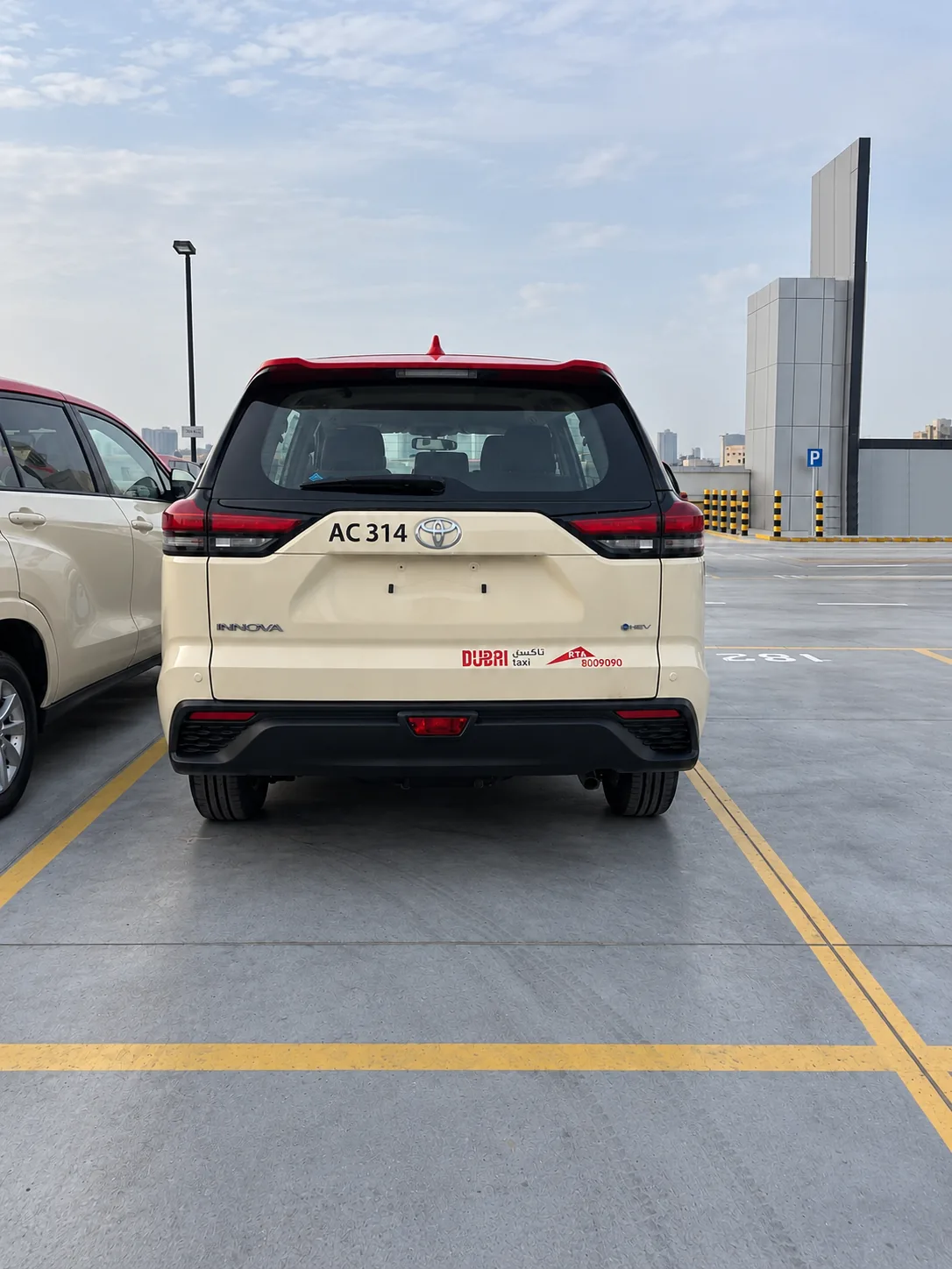 Rear view of a Dubai Taxi in red and cream livery showing tailgate graphics.
