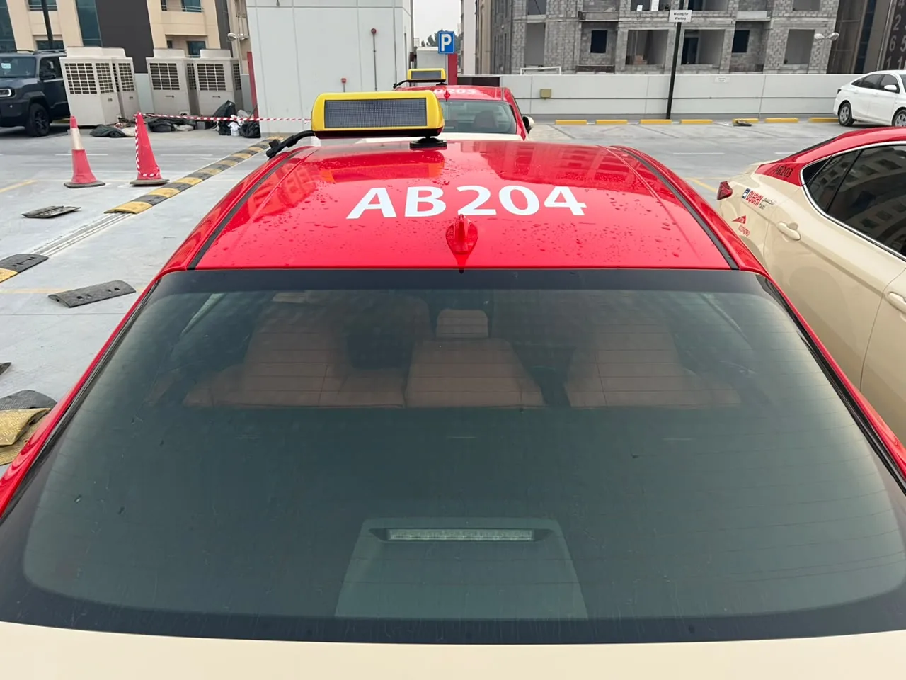 Red roof of Dubai Taxi AB204 with its large white fleet number.