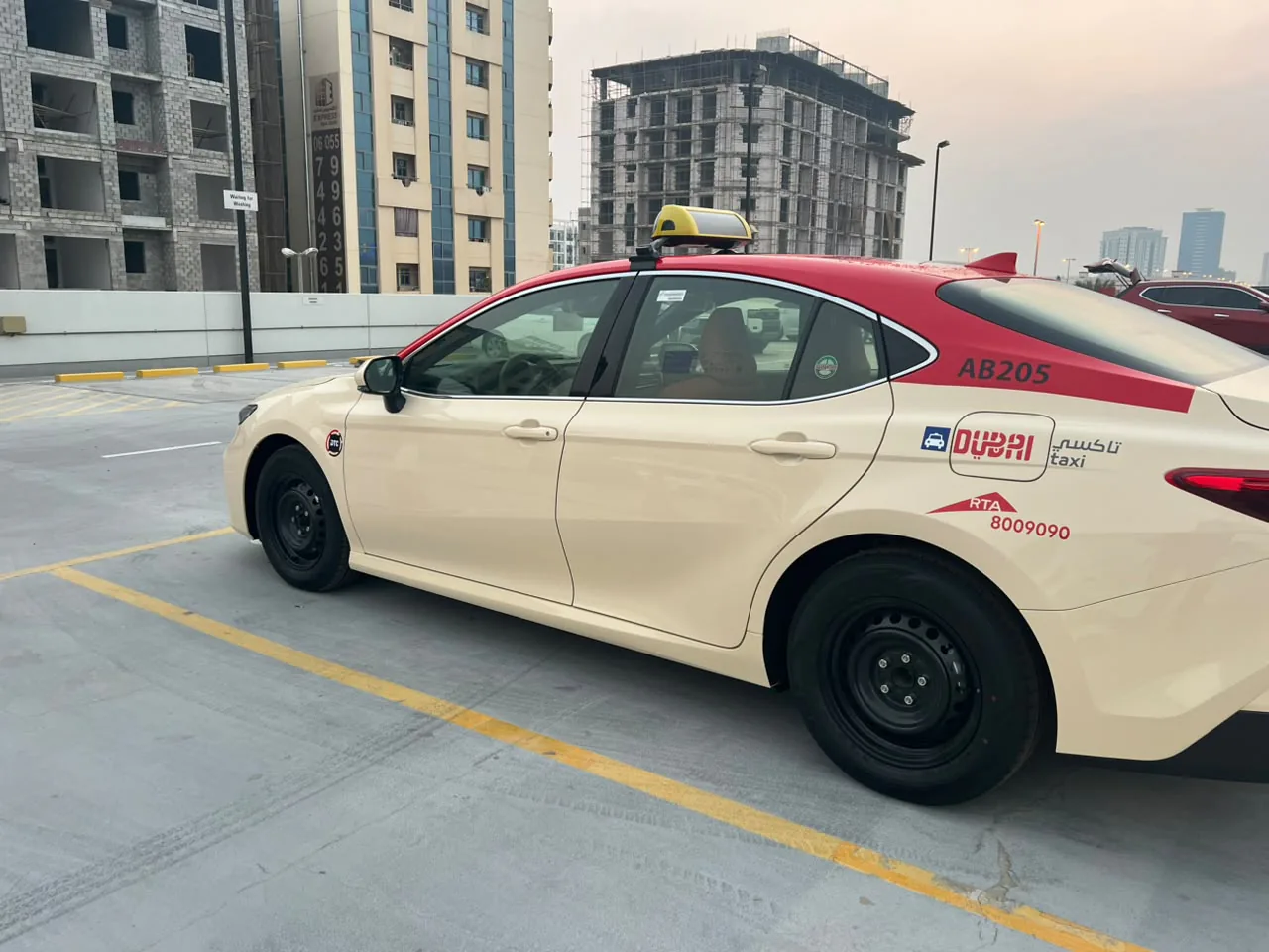 Dubai Taxi Toyota Camry AB205 in red and cream livery, front three-quarter view.