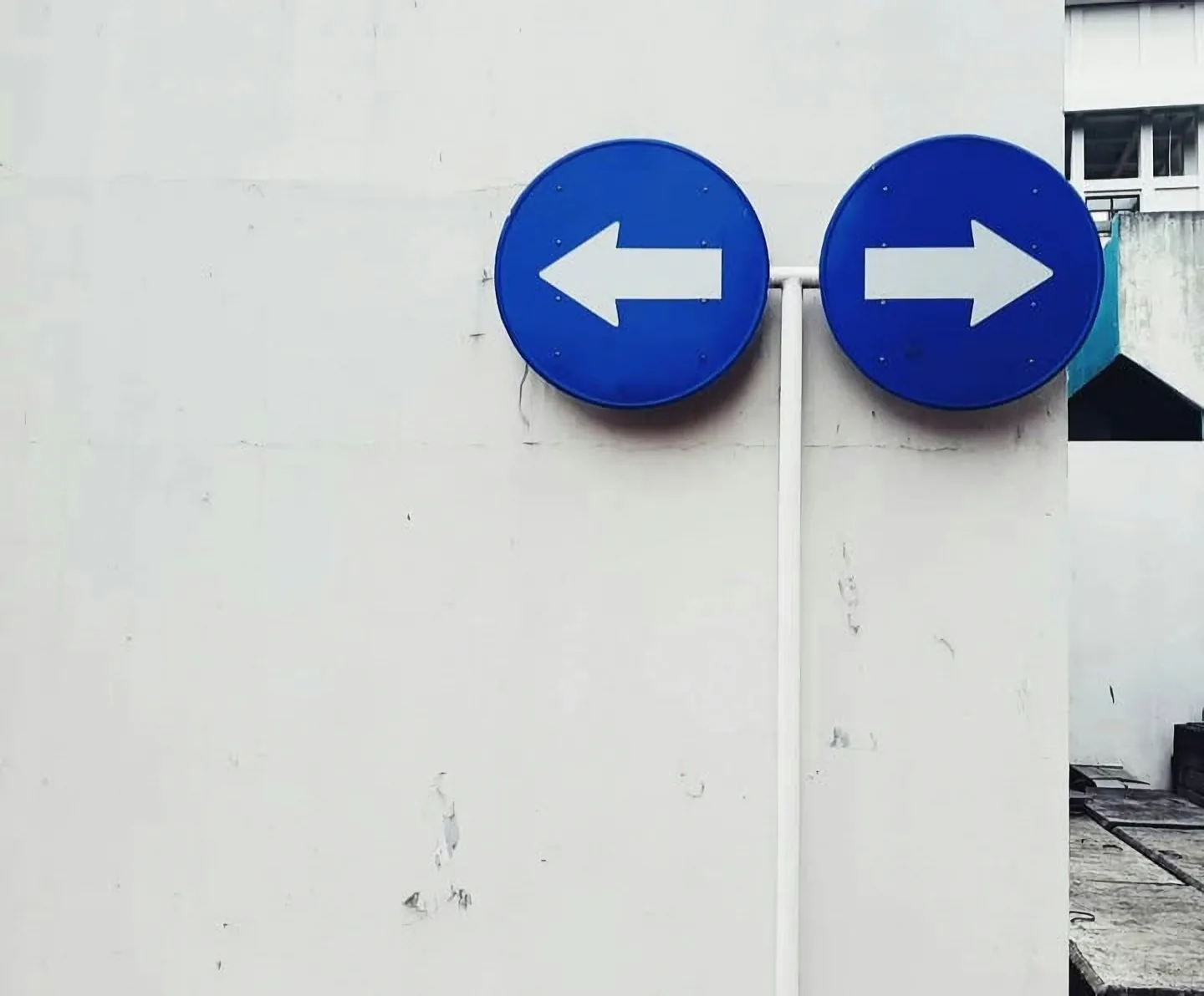 Two blue circular directional signs with opposing white arrows mounted on a wall.
